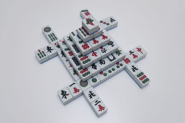 High-angle view of intricately arranged mahjong tiles on a white surface, showcasing traditional symbols.