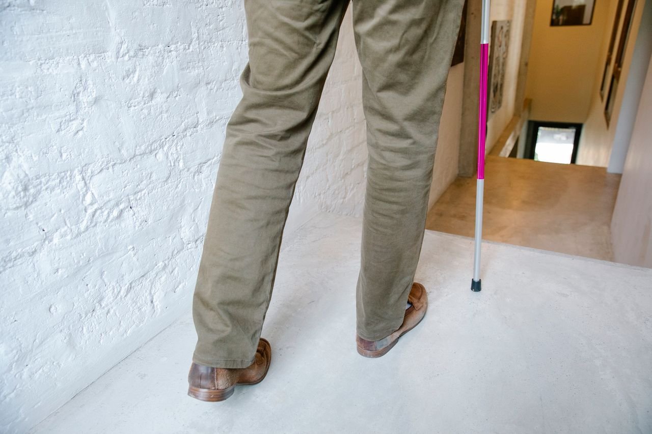 A person using a walking stick navigates a hallway, symbolizing independence and mobility support.